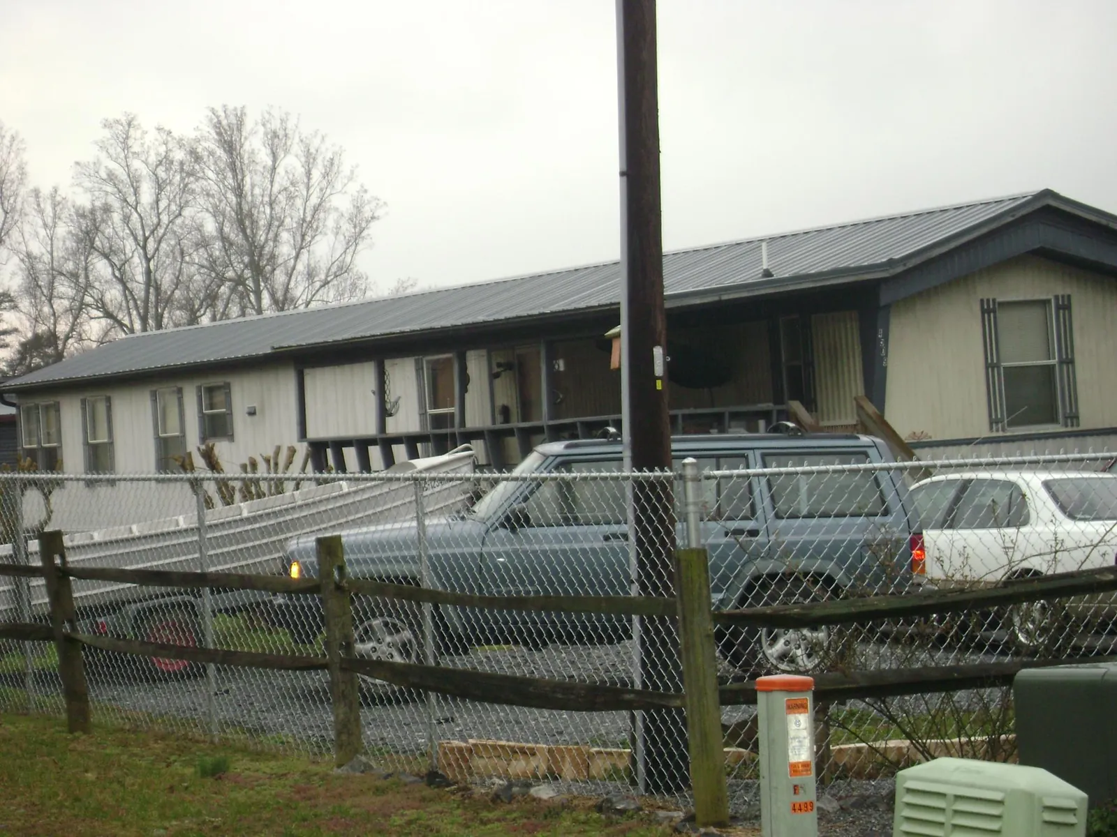 Dark metal roof on a long single story building behind a chain link fence in Prescott
